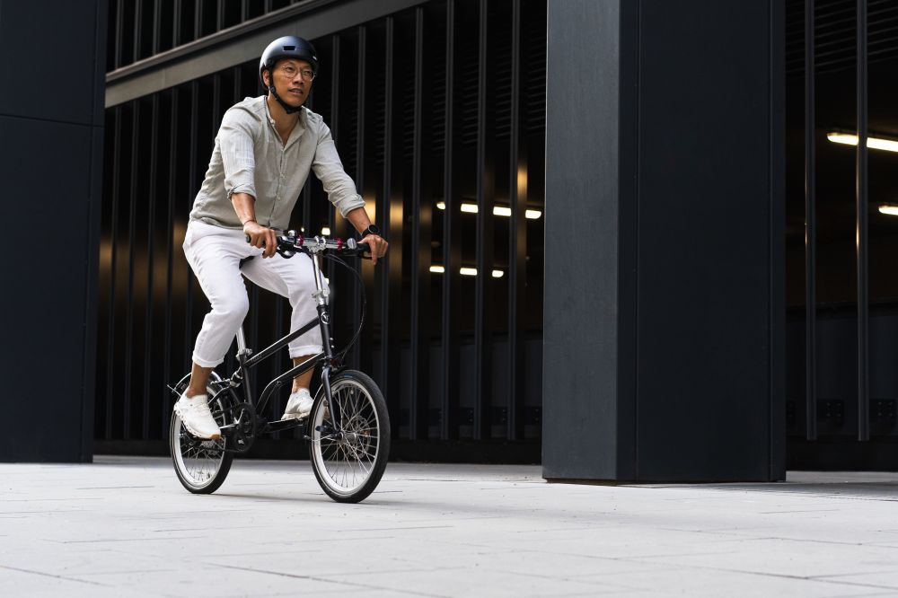 Radfahrer im legeren Businessoutfit auf einem Faltrad